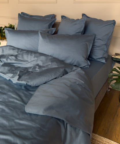 Lit fait avec un drap-housse en satin de coton bio bleu minéral, linge de lit fabriqué dans les Vosges 
