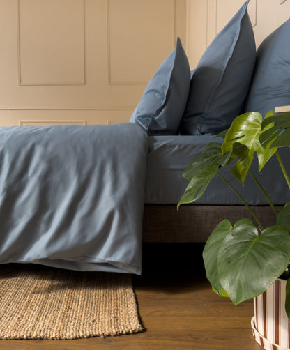 Élastique tête et pied d'un drap-housse en satin de coton bio bleu minéral, bien tendu sur le matelas 