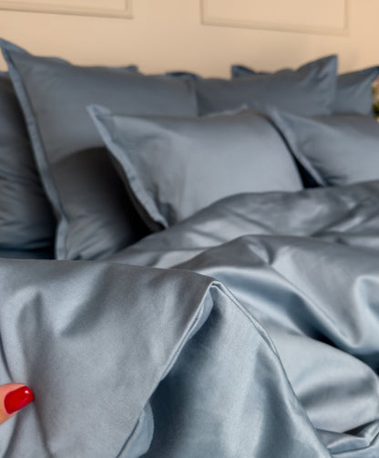 Finition bouteille à large rabat d'une housse de couette en satin de coton bio bleu minéral 